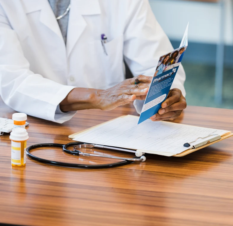 Doctor reviewing brochure at a desk.