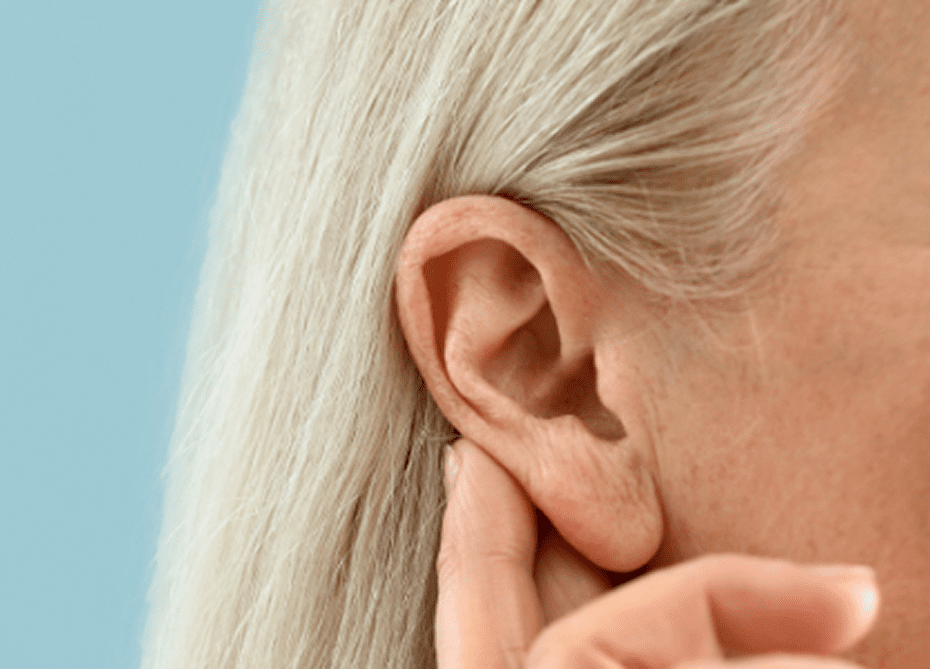 Elderly woman touching her ear gently.